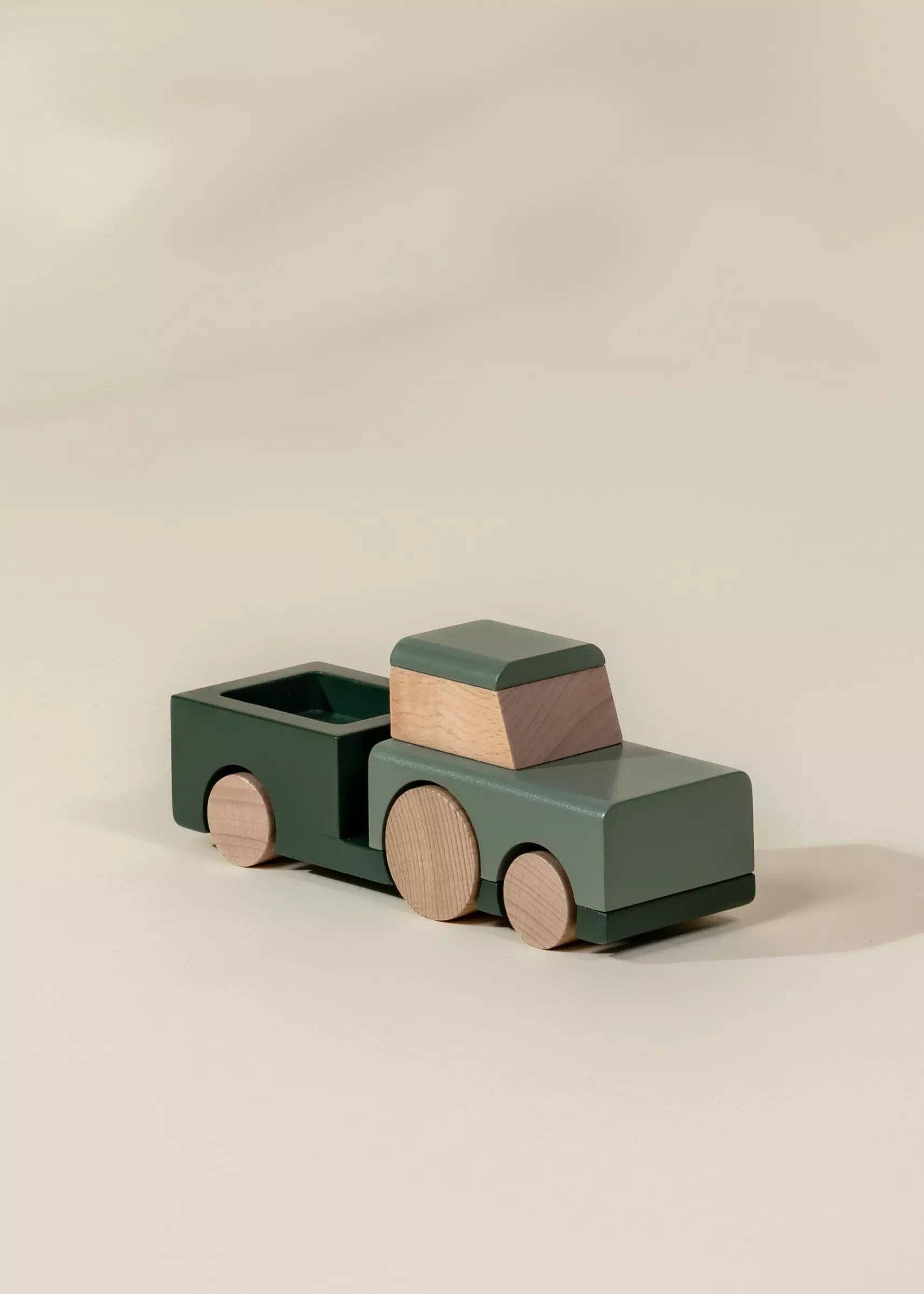 Wooden toy truck with green body and brown accents on a beige background