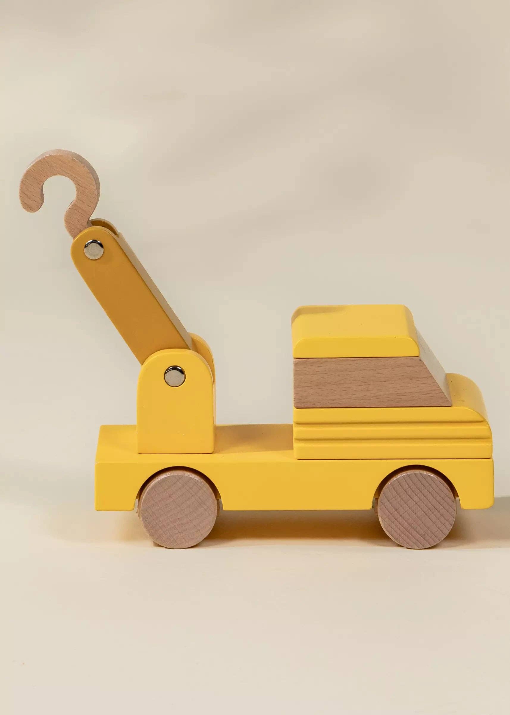 Yellow toy tow truck with a hook on a beige background