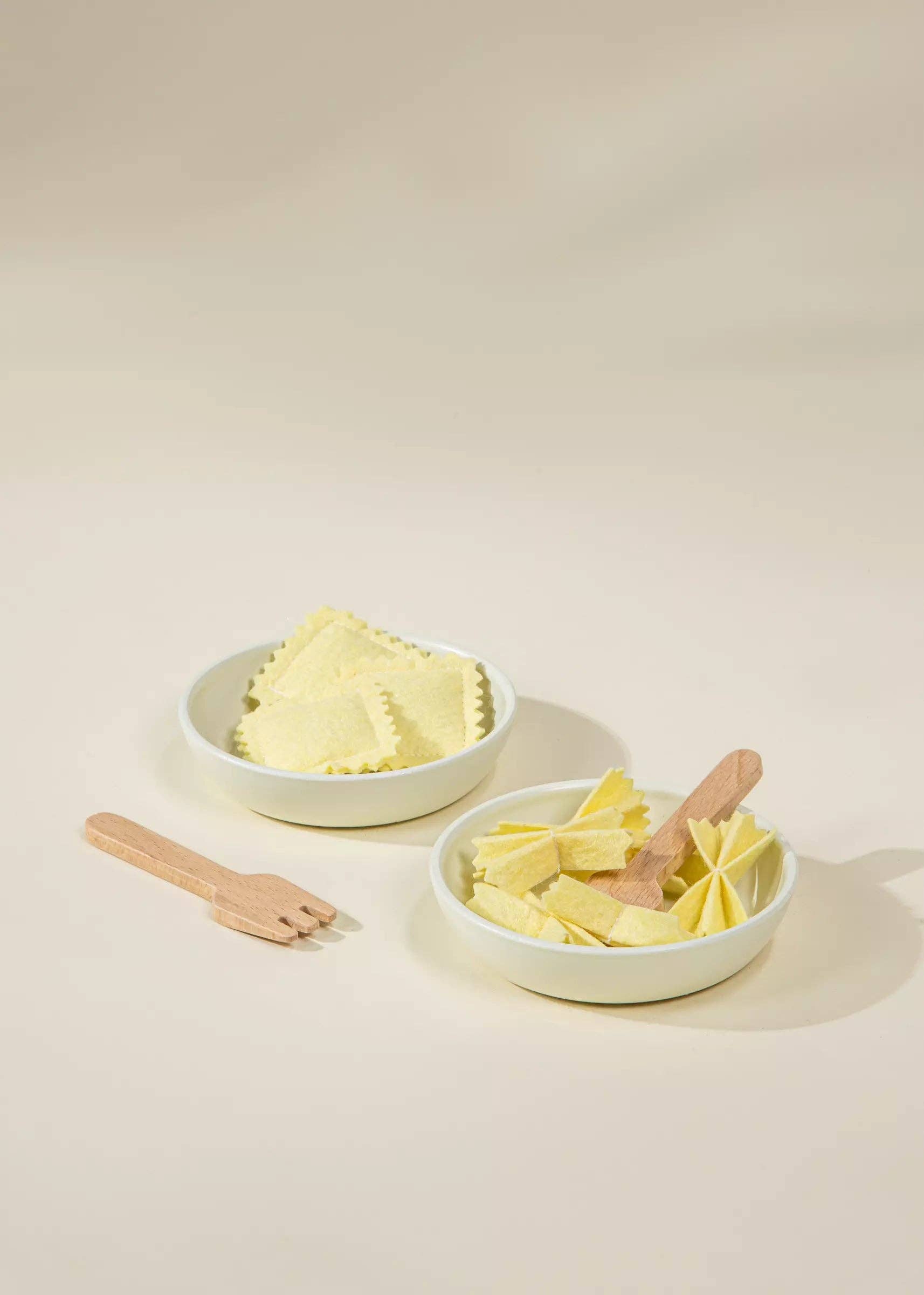 Two white bowls with ravioli on a beige background