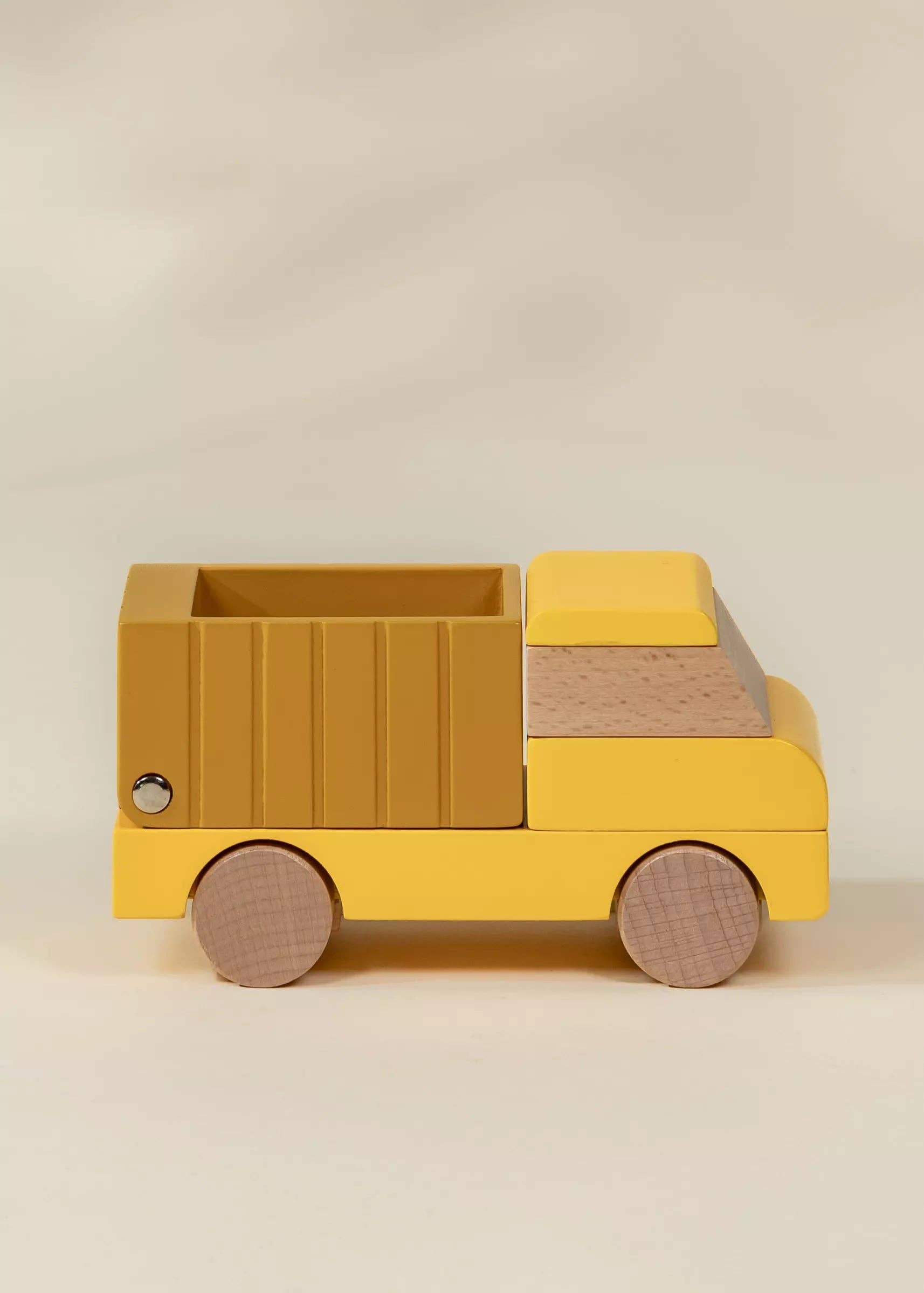 Yellow toy truck with wooden accents on a beige background