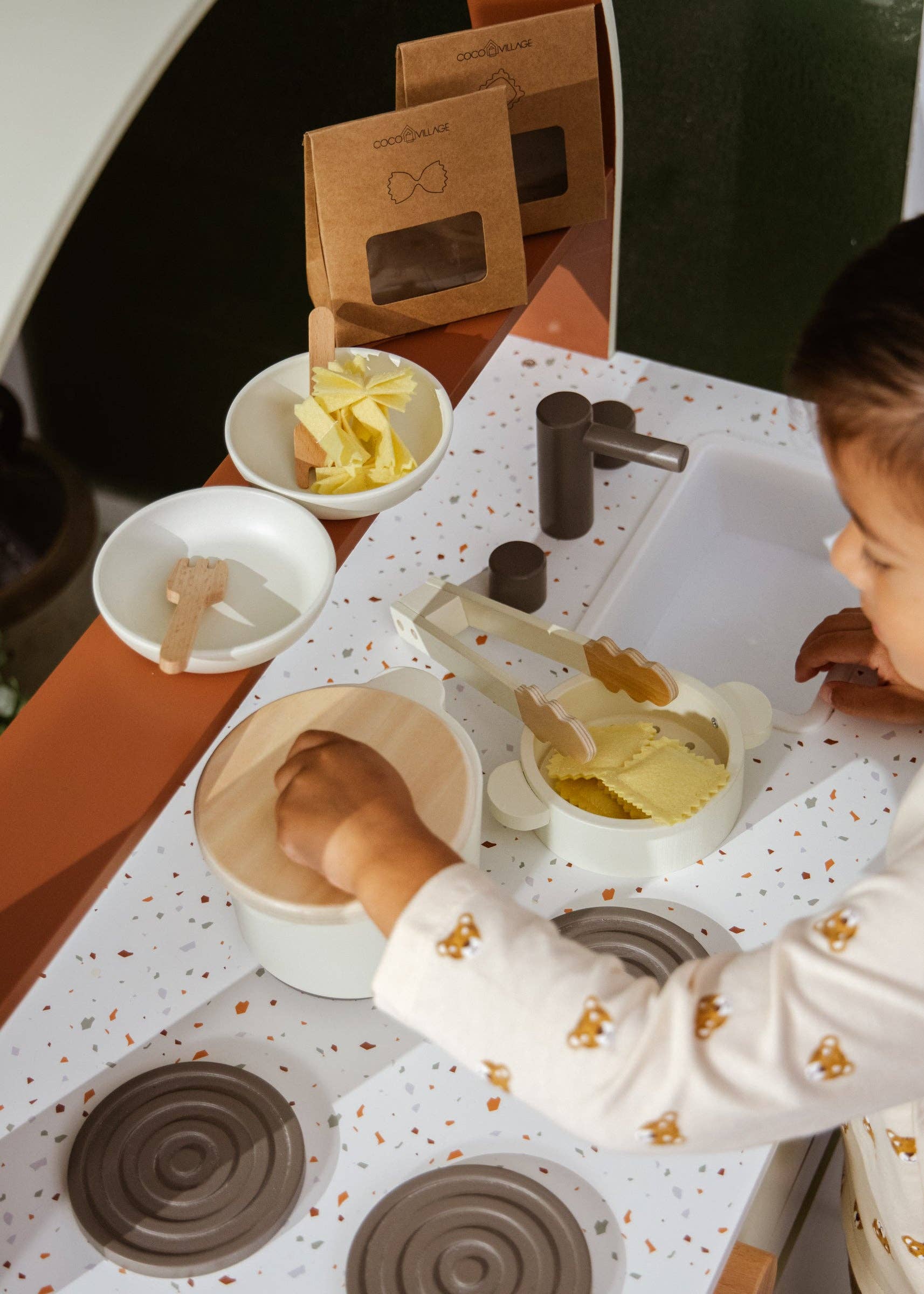 Child playing with play dough at a table with various play items.