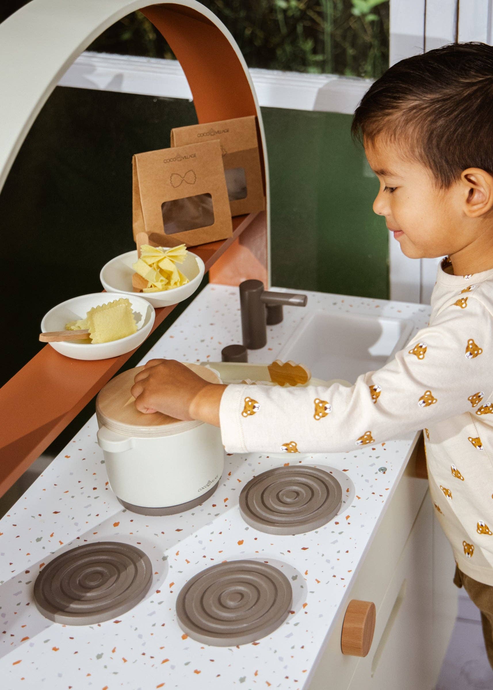 Child playing with a toy kitchen set outdoors