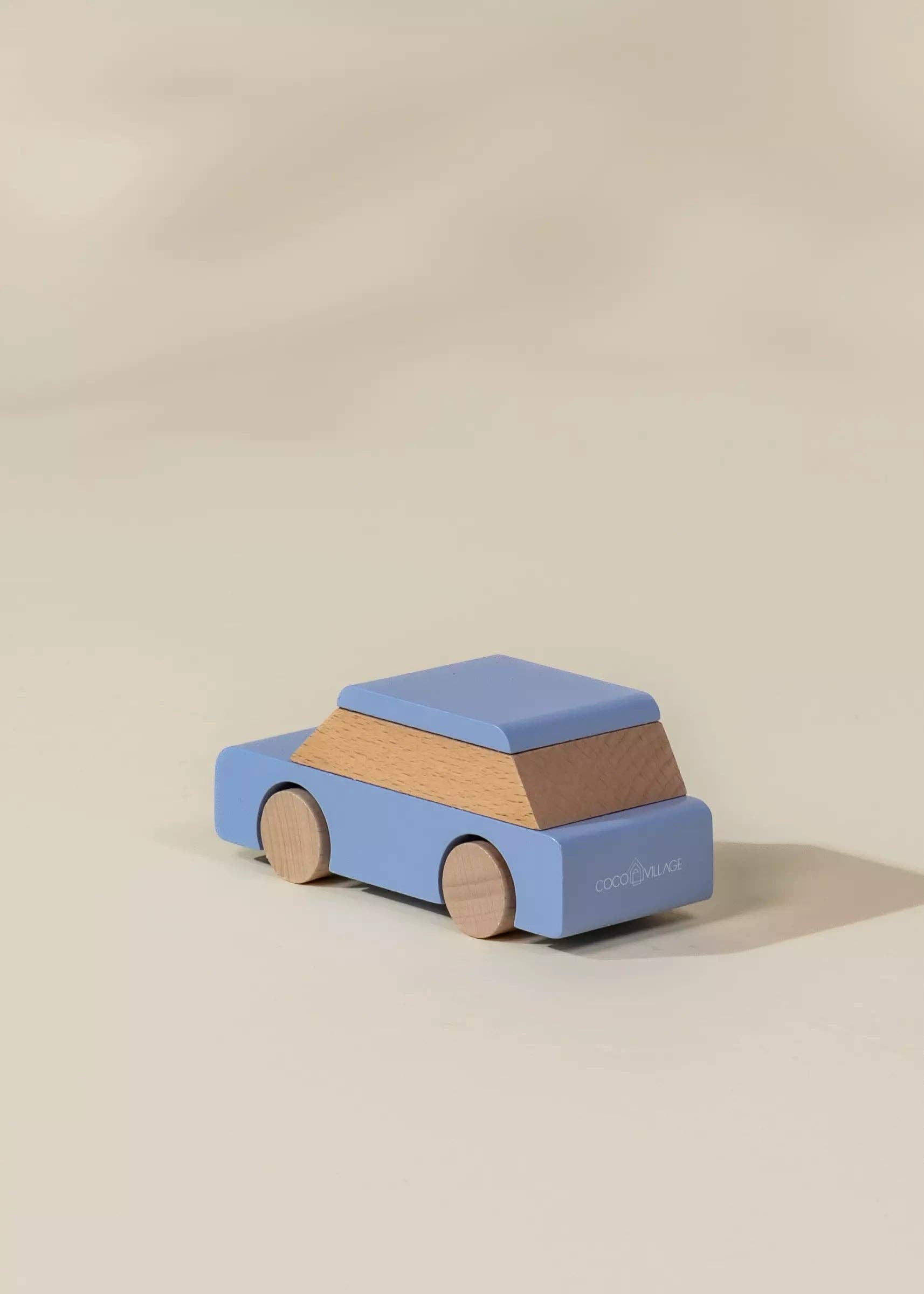 Wooden toy car with blue top and brown body on a beige background