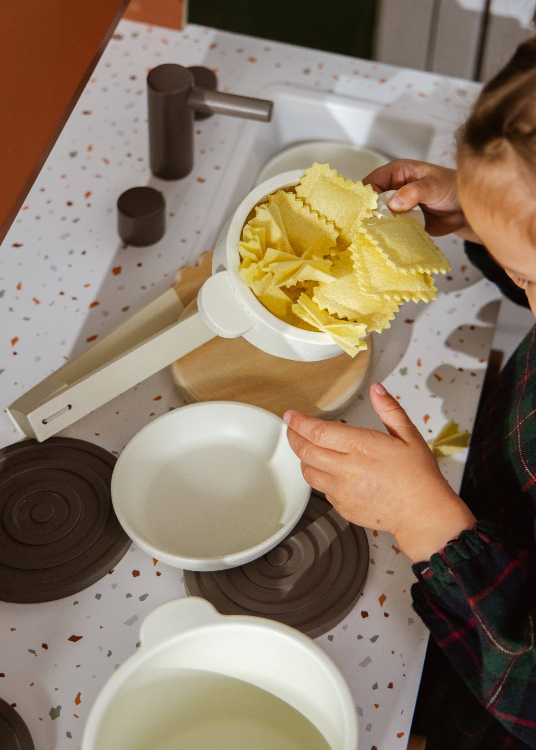 Person using a pasta press to make lasagna noodles on a speckled countertop.