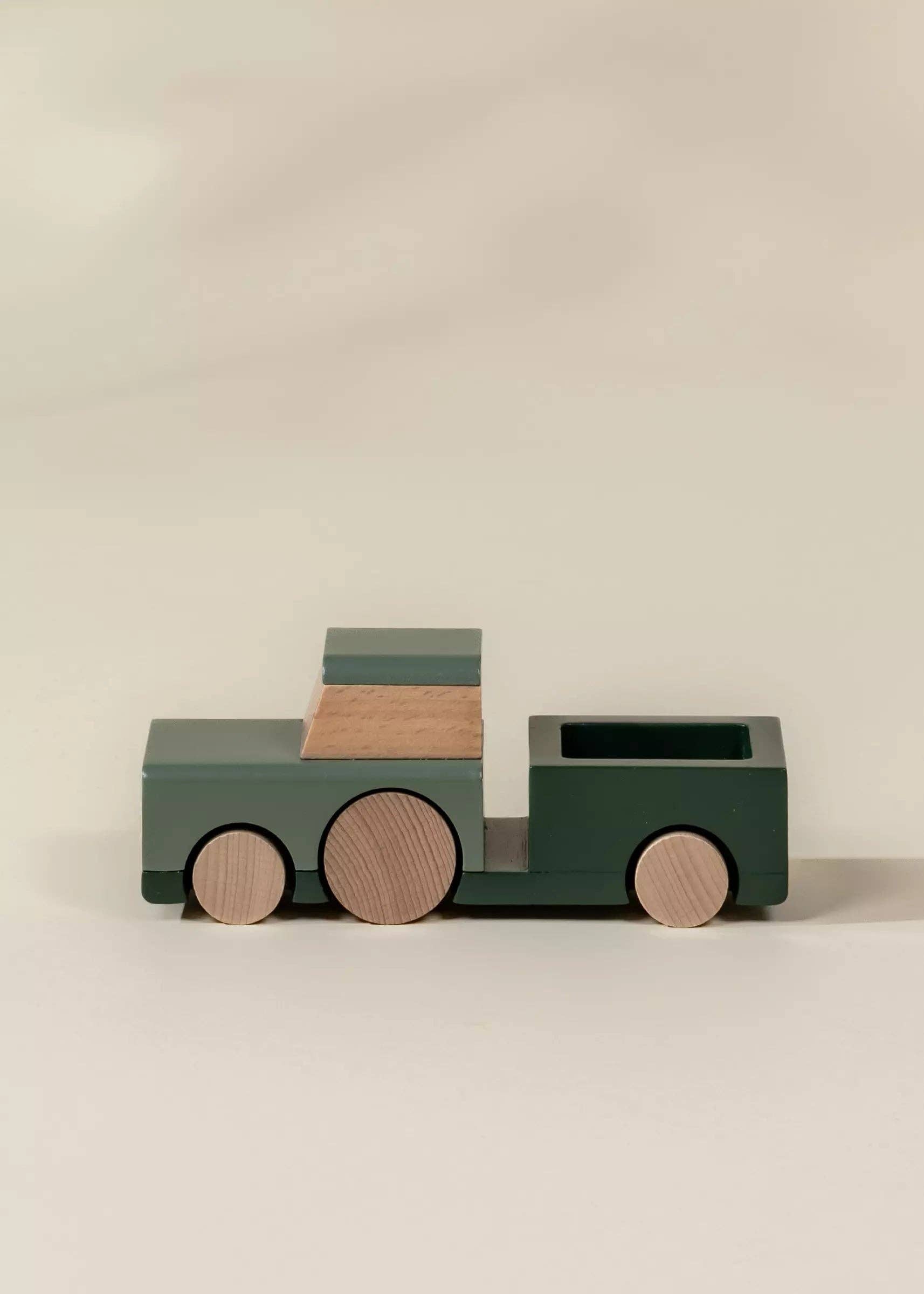 Wooden toy truck with green body and brown wheels on a beige background