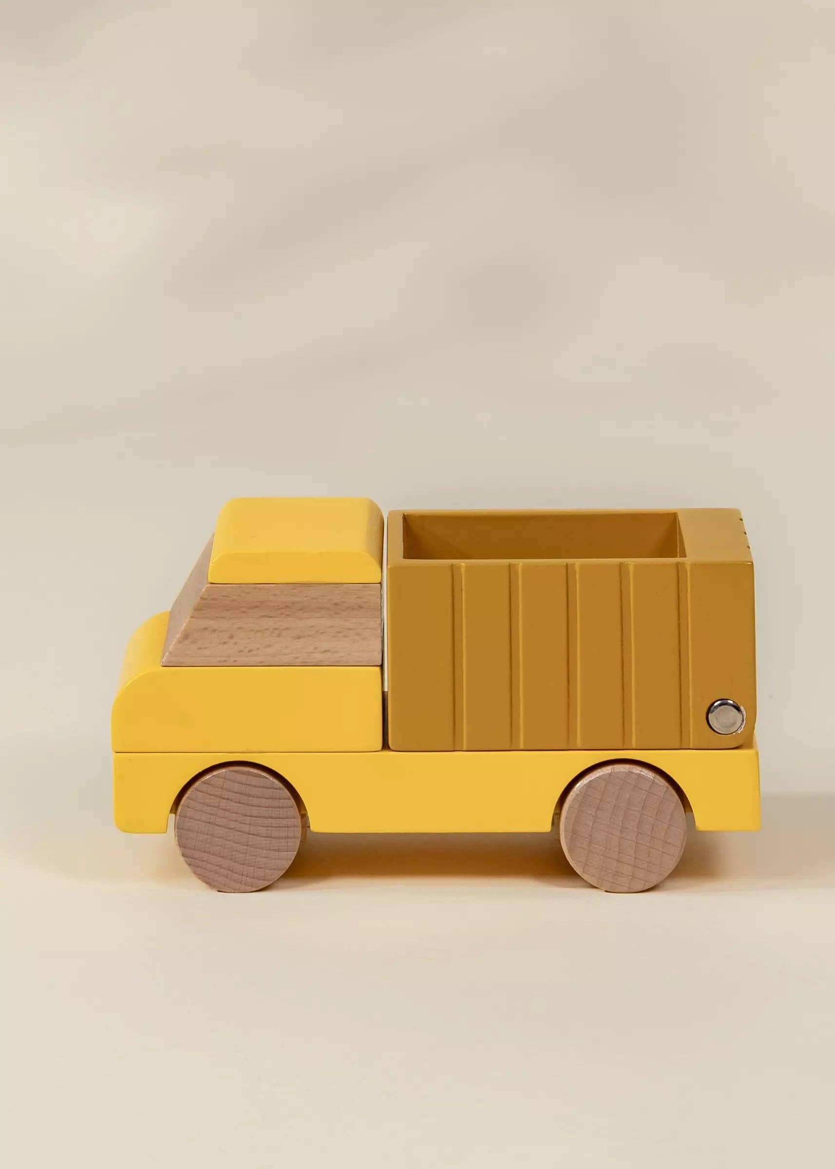 Yellow toy truck with wooden accents on a beige background