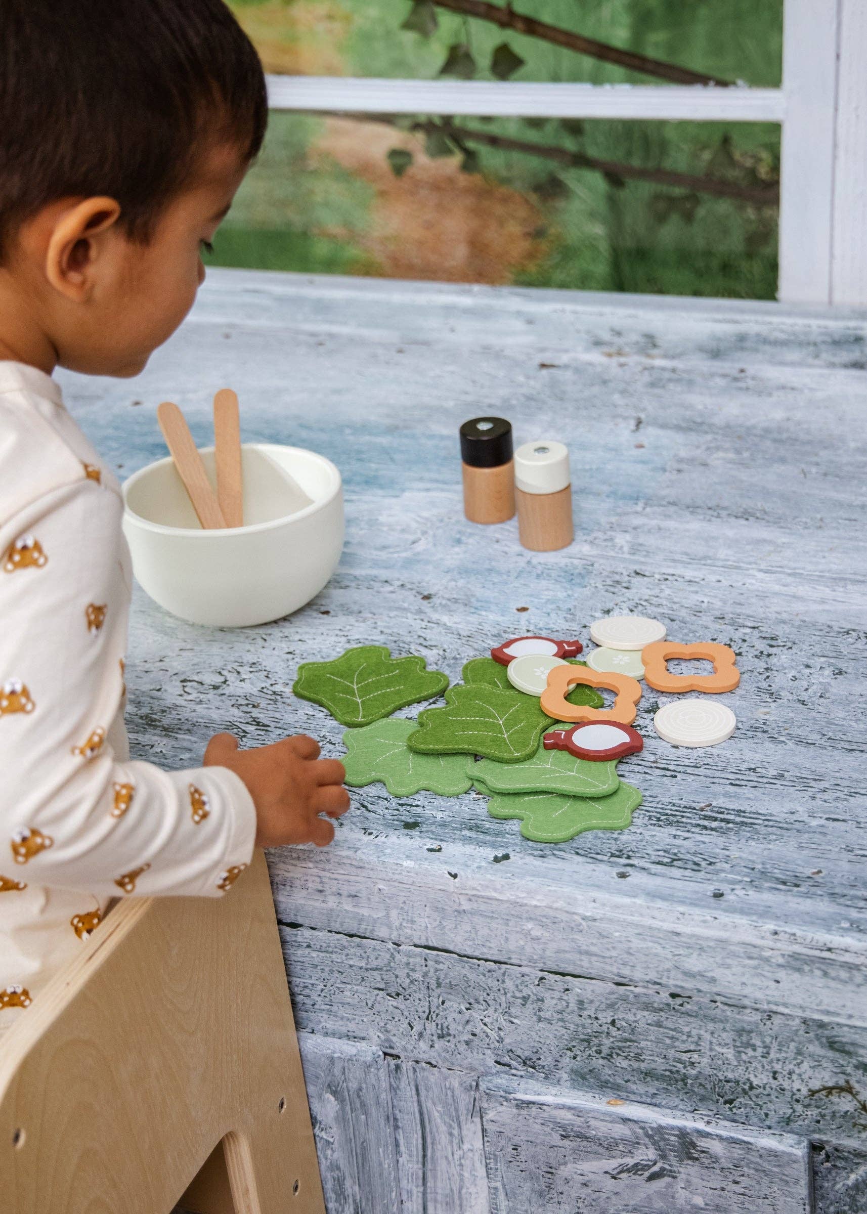 Child playing with felt food on a wooden surface