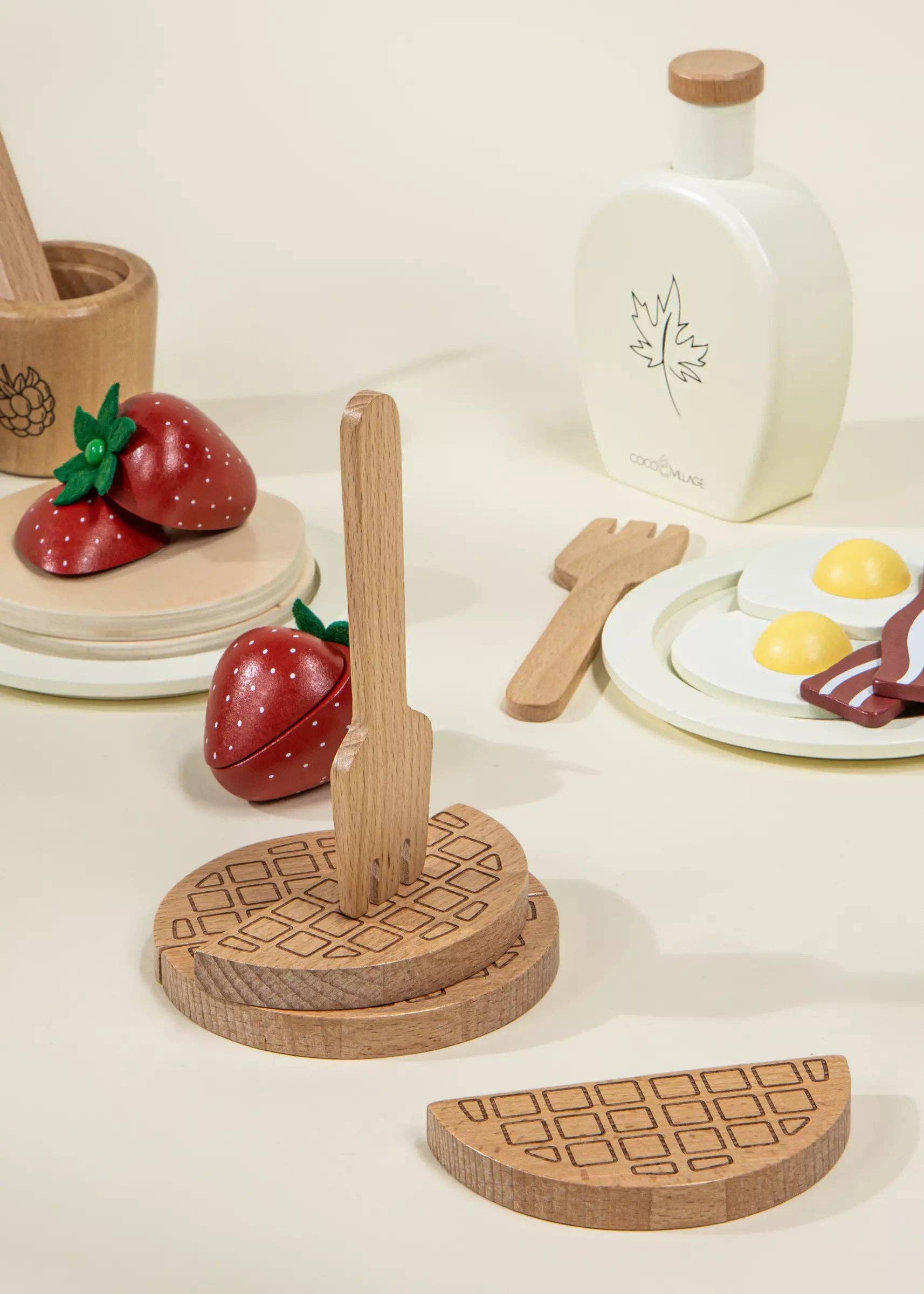 Wooden toy food set with fruits, eggs, and a bottle on a light surface.