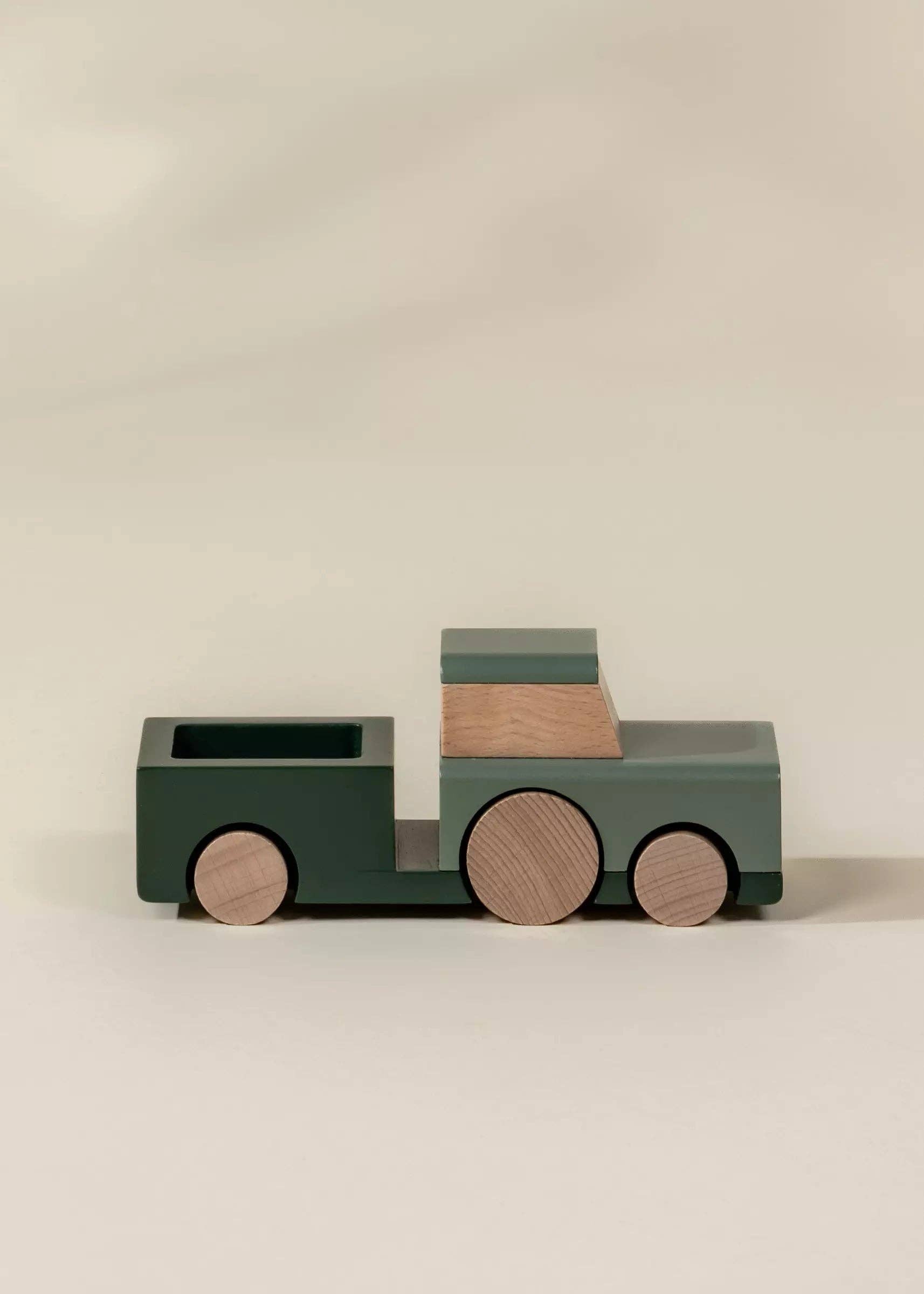 Wooden toy truck with a green body and brown wheels on a beige background