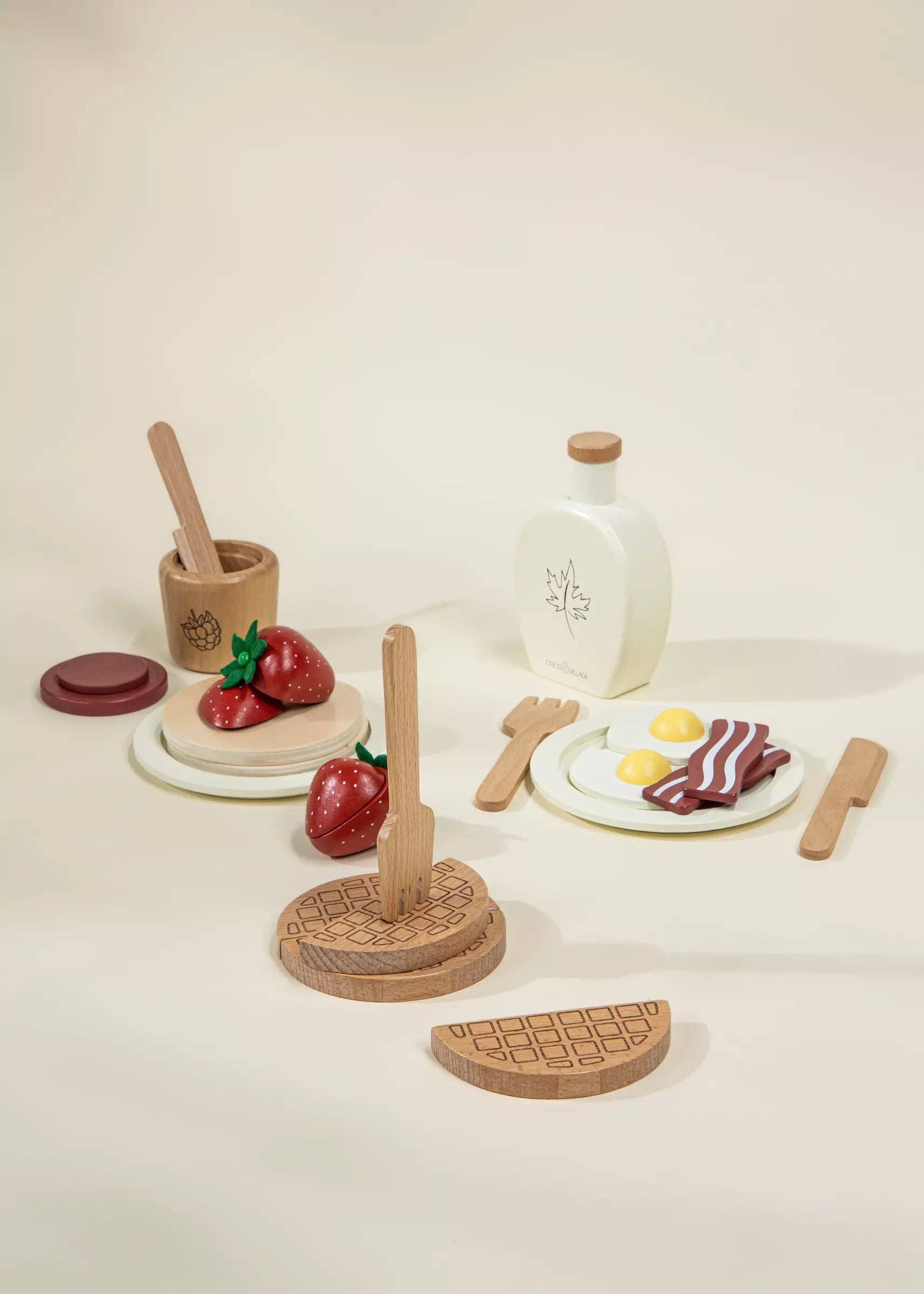 Set of wooden toy food items including fruits, a bottle, and utensils on a light background