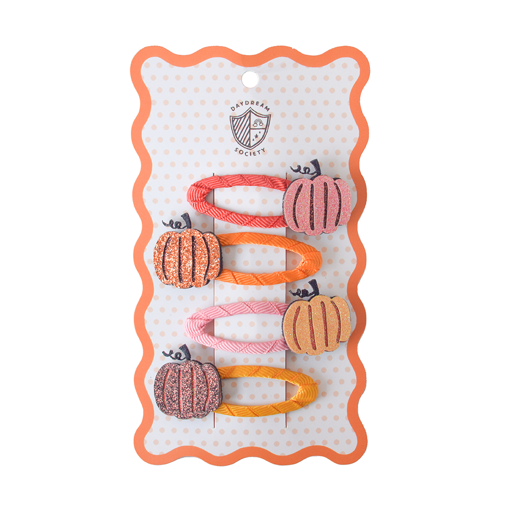 Set of pumpkin-shaped hair accessories on a branded card with a white background