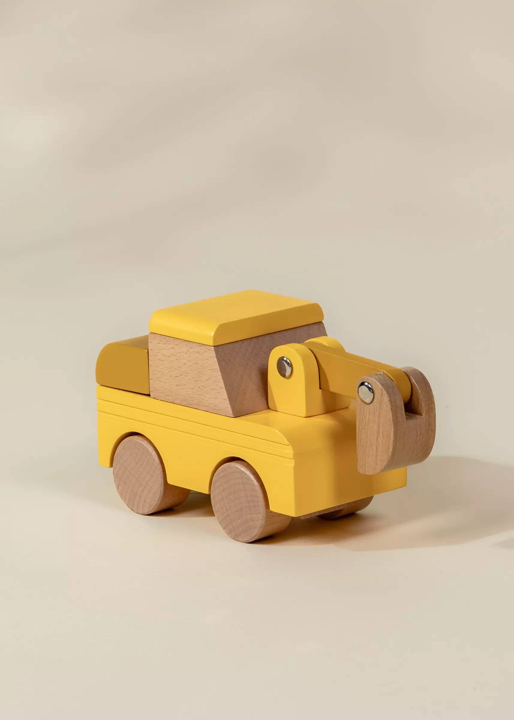 Wooden toy truck with a yellow body and brown accents on a beige background