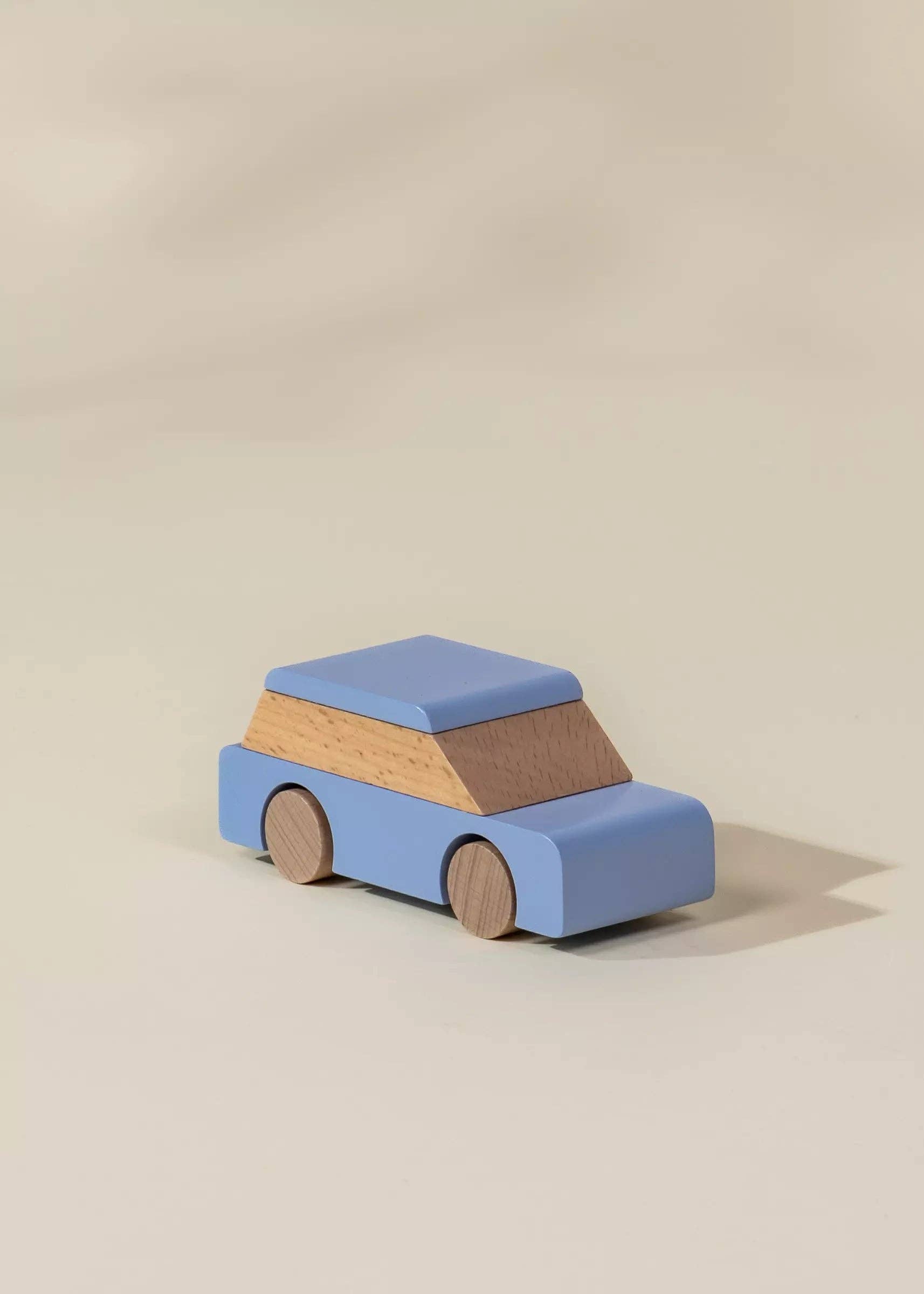 Wooden toy car with a blue body and brown roof on a beige background