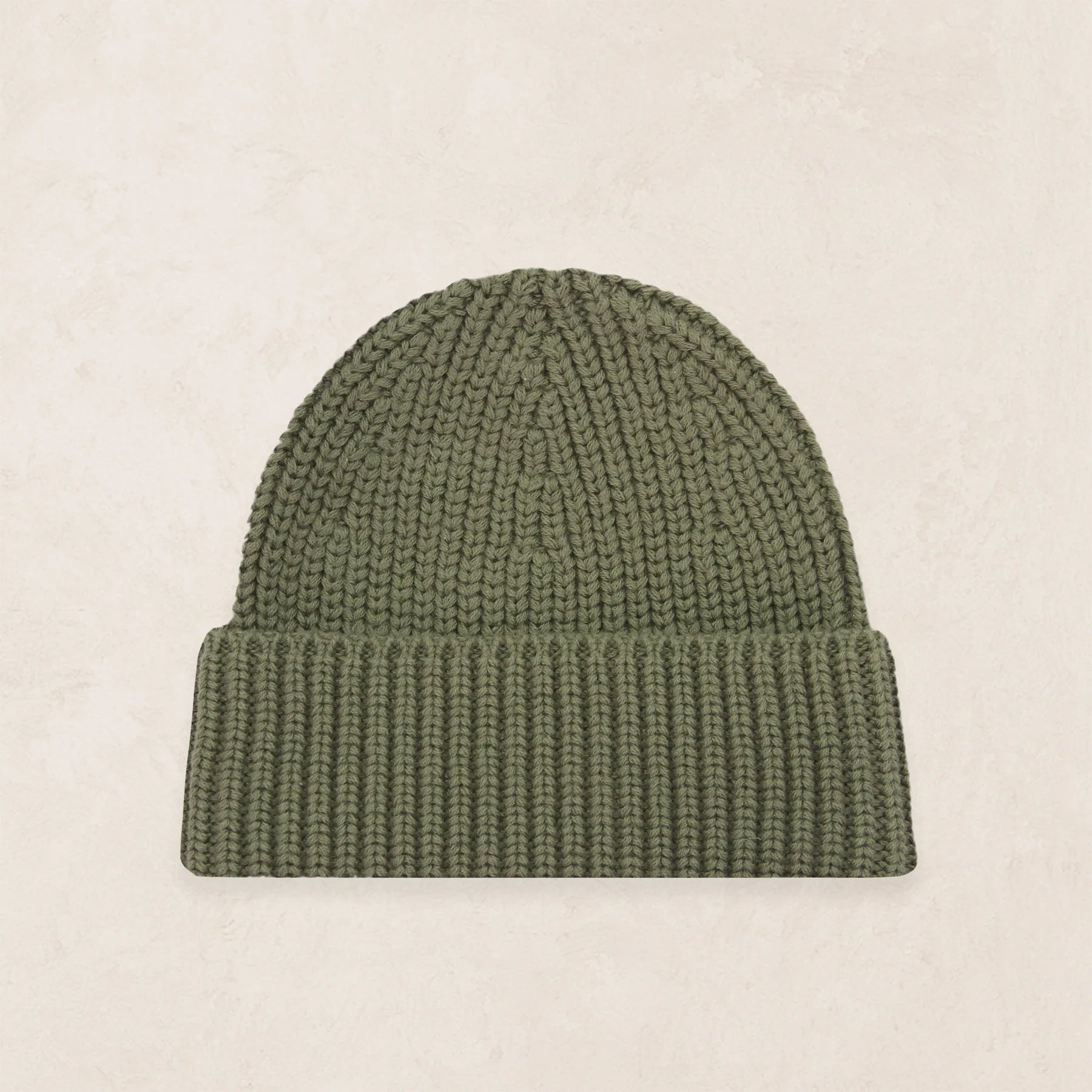An olive green ribbed knit beanie hat, displayed flat against a light beige textured background.